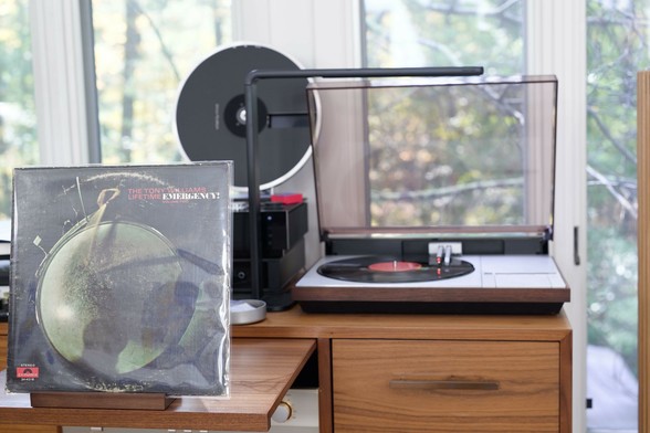 The Tony Williams Lifetime - Emergency, Volume II LP cover.

A drumhead, shot from above, being hit.

The black LP plays on a vintage, restored Bang & Olufsen Beogram 4000 linear-tracking turntable to the right.
