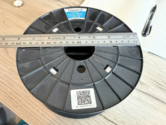 A large spool of white PETG 3D printing filament with a ruler on top showing the diameter of the spool at 200mm