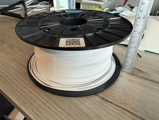 A large spool of white PETG 3D printing filament with a ruler alongside showing the width of the spool at just under 90mmm