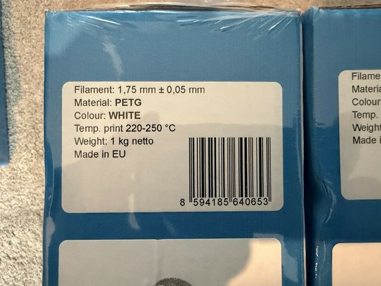 Image shows a label on a package of 3D printing filament. Details include filament diameter (1.75 mm), material (PETG), color (white), recommended printing temperature (220-250 °C), weight (1 kg)