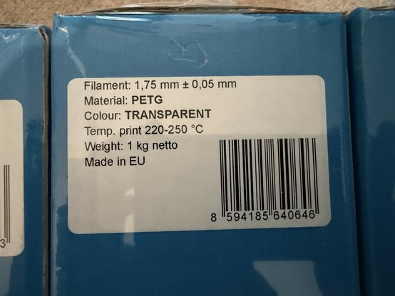 Label on a spool of 3D printing filament. Specifications include filament diameter (1.75 mm ± 0.05 mm), material (PETG), color (transparent), recommended printing temperature (220-250 °C), weight (1 kg)